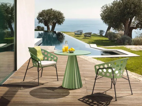 Le petit fauteuil Bolle avec la table Plissè dans un espace extérieur